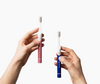 Two hands grasping a blue toothbrush and a pink toothbrush-Cheeky