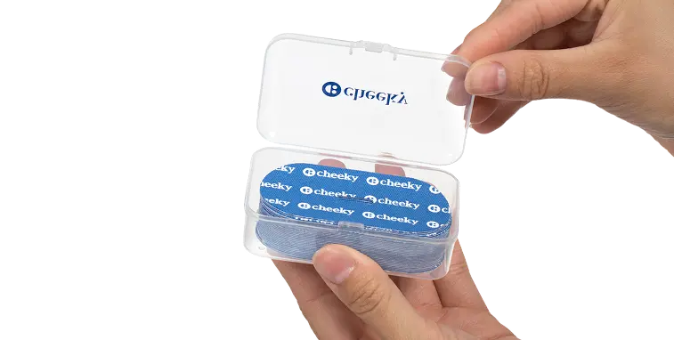 Cheeky dental floss container held by a hand on a white background